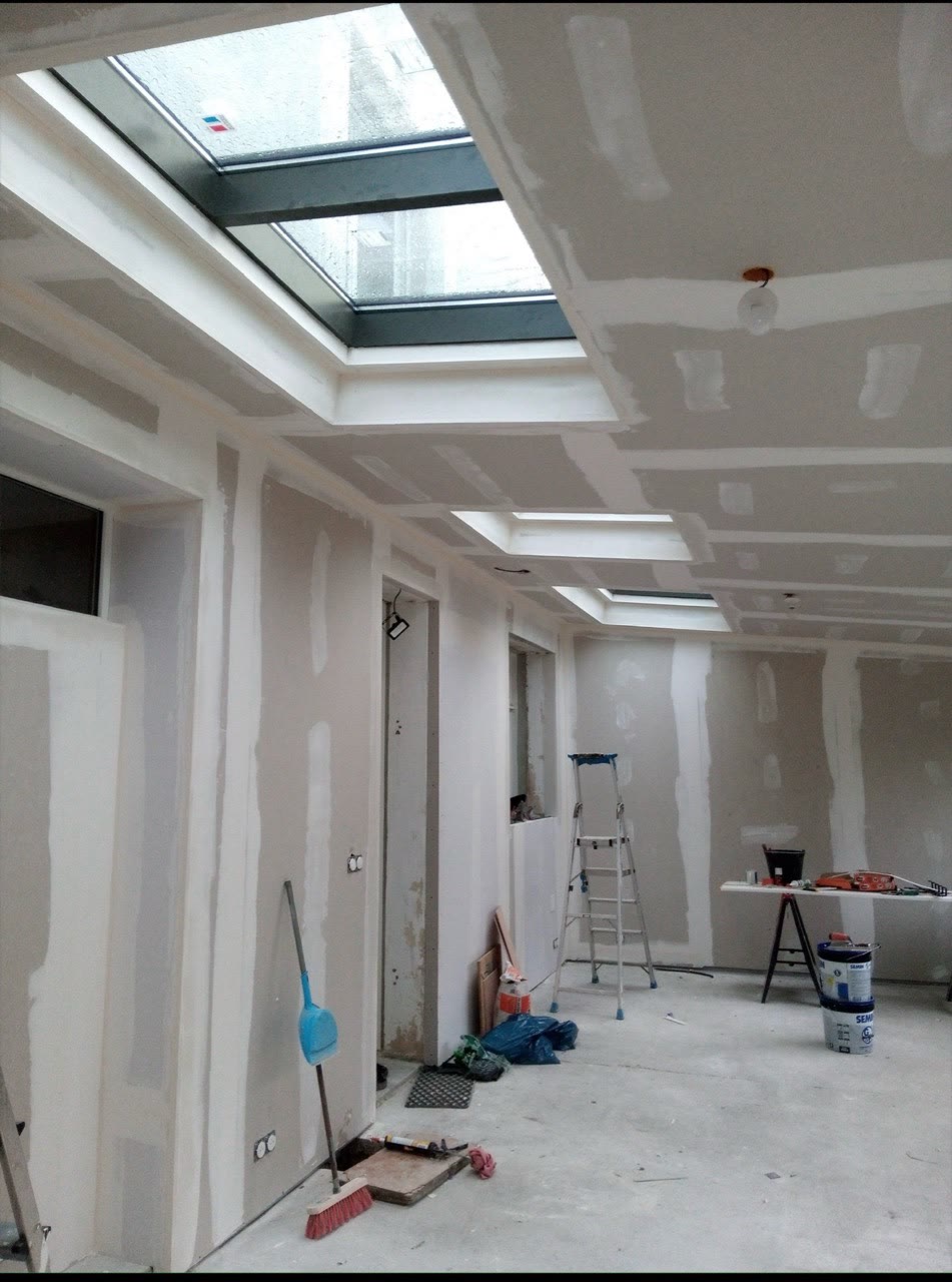 Plafond en plaques de plâtre en cours de finition, avec plusieurs puits de lumière